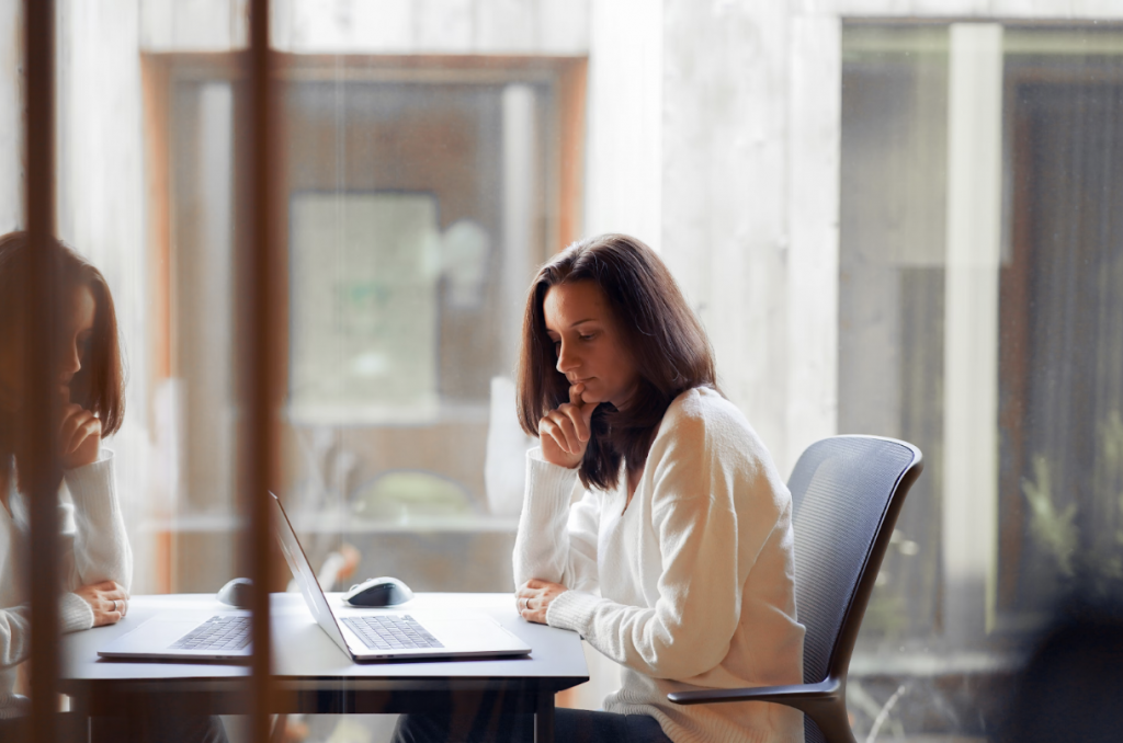 Woman Sitting at a Desk and Staring Intently at Her Laptop